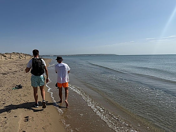 Varios vecinos caminando por la playa hacia Alicante.