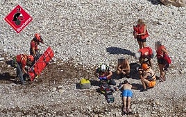 Los bomberos despliegan la camilla para evacuar al herido, tendido en el suelo.