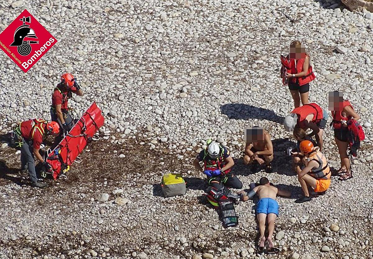 Los bomberos despliegan la camilla para evacuar al herido, tendido en el suelo.