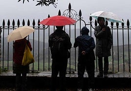Unas personas bajo la lluvia, con sus paraguas.