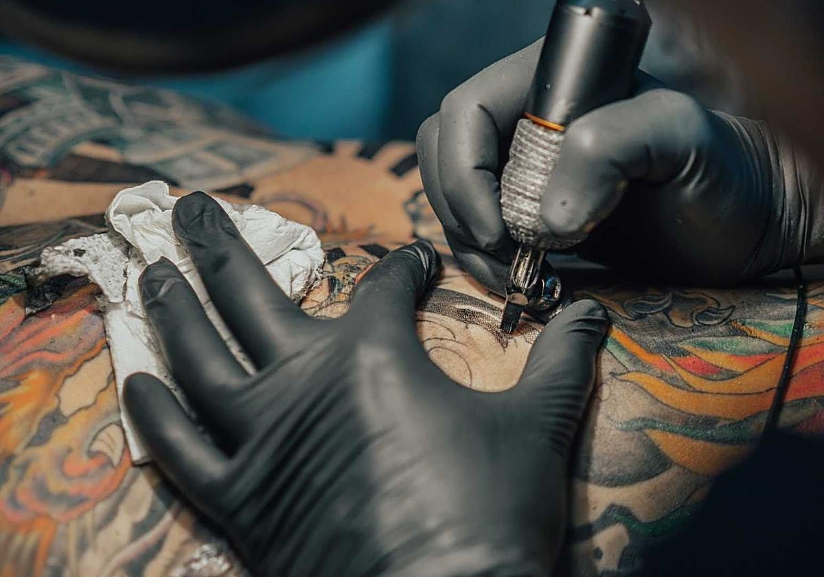 Artista realizando un tatuaje.