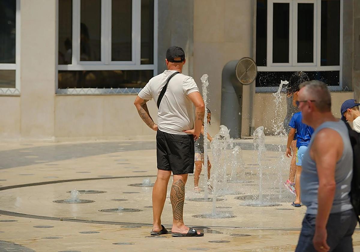 Turistas buscan aliviarse del calor en una fuente de la Explanada.