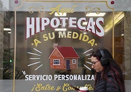 Una joven pasa por delante de una sucursal que oferta hipotecas.