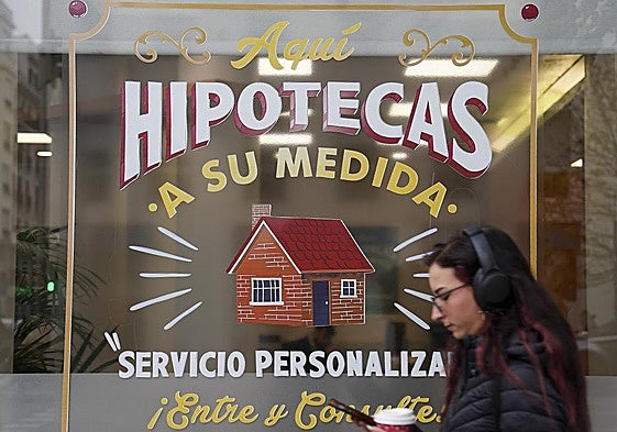 Una joven pasa por delante de una sucursal que oferta hipotecas.