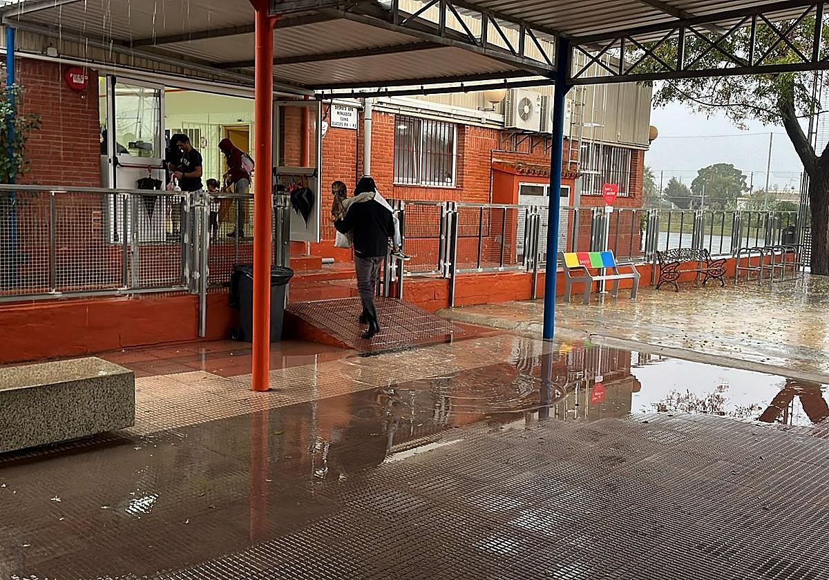 Una madre lleva a brazos a su hijo en un colegio de Dénia durante un día de lluvias.