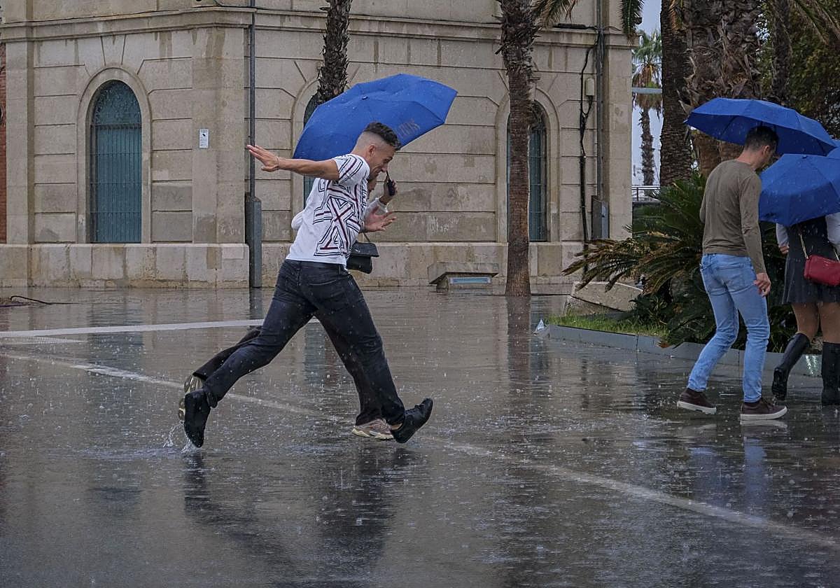 Several people shield themselves from the rain in Alicante.