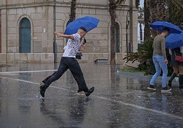 Varias personas se protegen de la lluvia en Alicante.