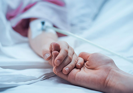Un adulto coge la mano de un niño hospitalizado.