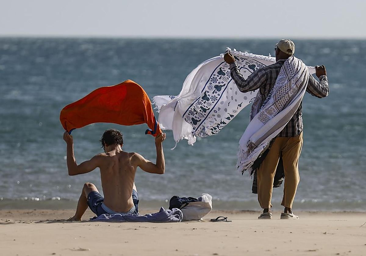 A couple collects their belongings from the beach due to the wind.