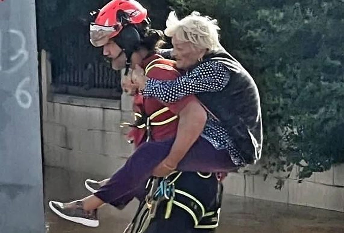 Un bombero carga a una mujer en brazos.