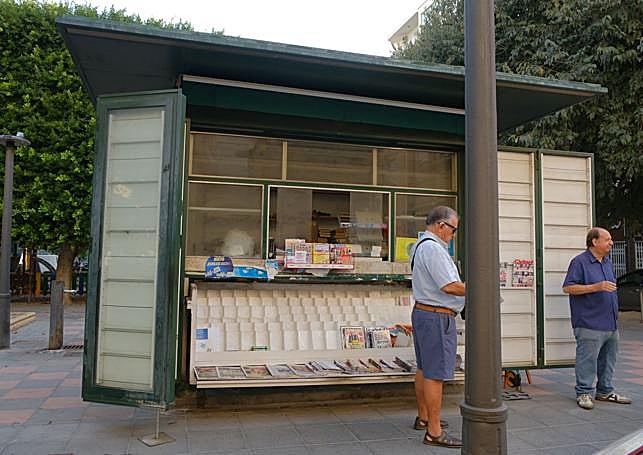 Julio en su quiosco con un vecino y cliente.