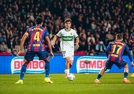 El centrocampista del Elche Rodrigo Mendoza conduce la pelota ante Araujo y Casadó.