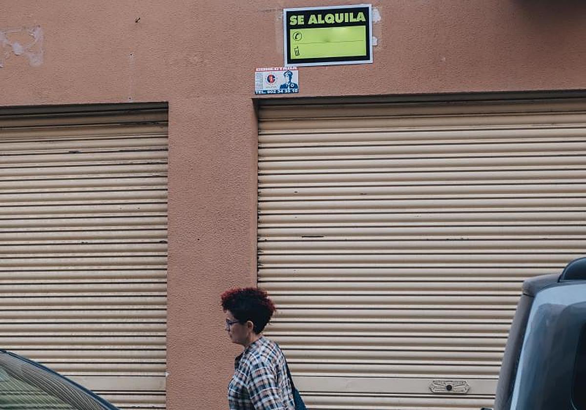 A woman walks under a 'For Rent' sign in Alicante.