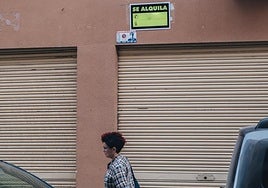 Una mujer pasa por debajo de un cartel de 'Se Alquila' en Alicante.