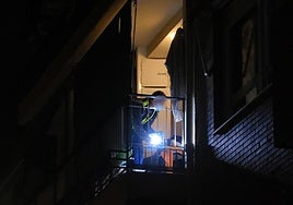 Un agente de la Científica en el balcón de la vivienda donde se ha producido el cirmen.